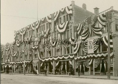 Downtown Beverly storefronts draped in flag bunting for Old Home Week, 1902